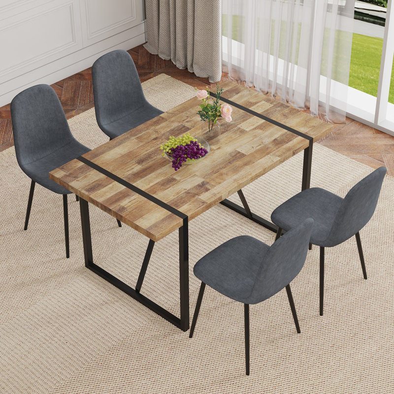 Ensemble de table et de chaises.Une table de salle à manger rectangulaire rétro minimaliste avec un dessus spécialement texturé et des pieds en métal noir. Elle est accompagnée de 4 chaises en tissu de lin gris foncé.
