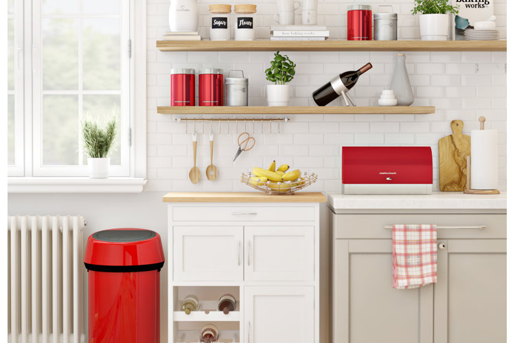 a minimalist kitchen with a bright red trash can
