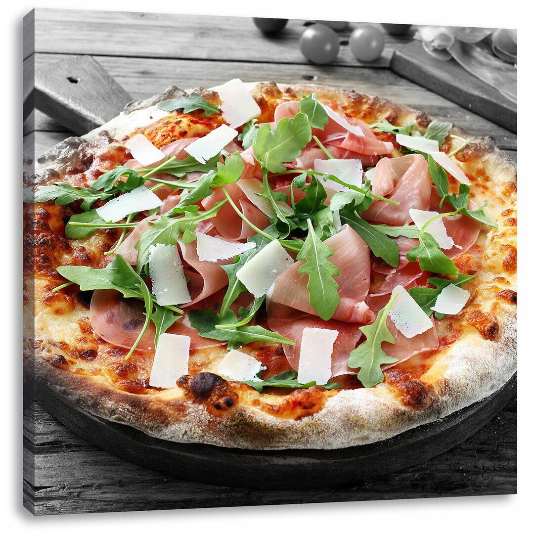 Leinwandbild Prosciutto Pizza mit Rucola und Parmesan auf rustikalem Holztisch