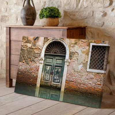 Toile une porte en bois arquée patinée avec des sculptures complexes comportant un art mural en fer forgé au-dessus d'une toile texturée
