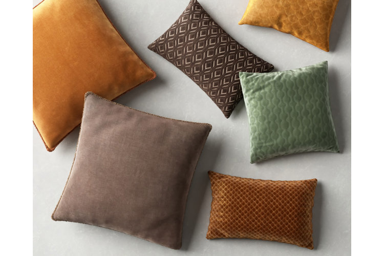 Flat lay of throw pillows in oranges, greens, and browns.