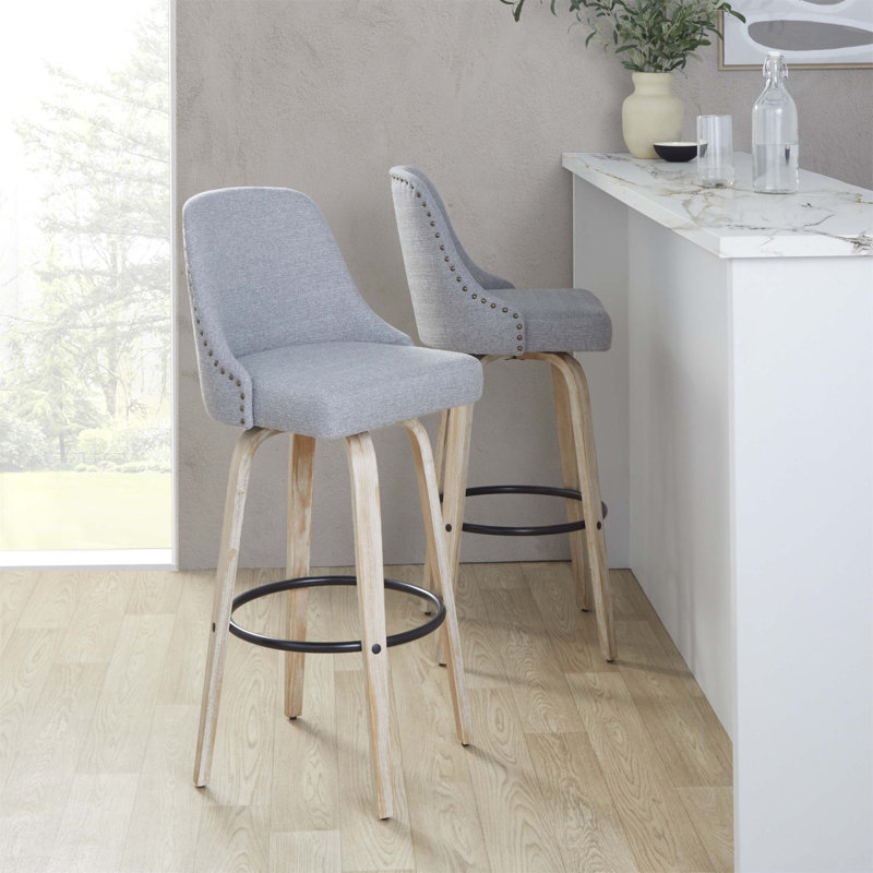 Ensemble de 2 tabourets pivotants de 30 pouces à hauteur fixe avec structure en bois blanchi, siège en tissu gris clair, garnitures cloutées en laiton et repose-pieds en métal noir.