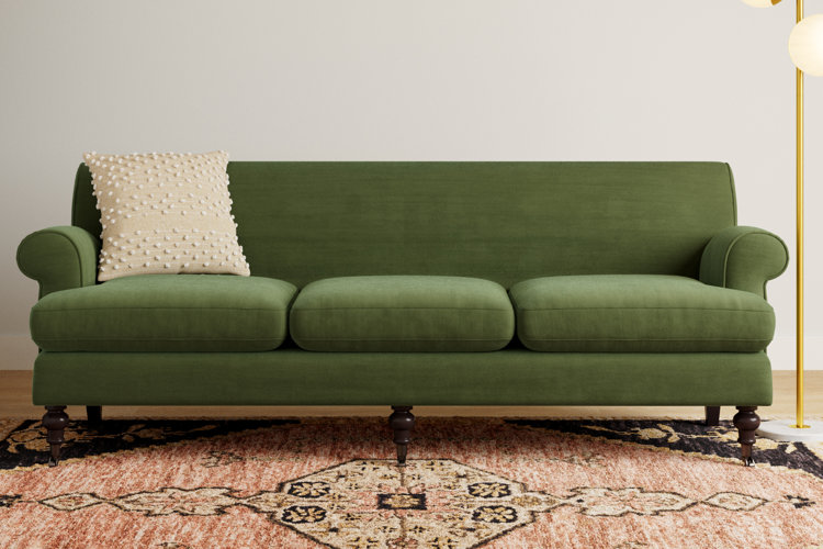 dark green sofa with carved legs and rolled arms