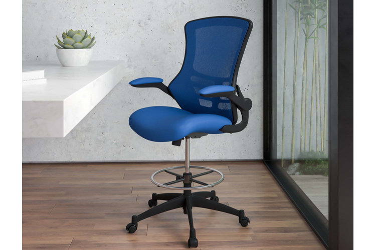 Blue drafting chair on a wooden floor beside a white marble table and a floor-to-ceiling glass window.