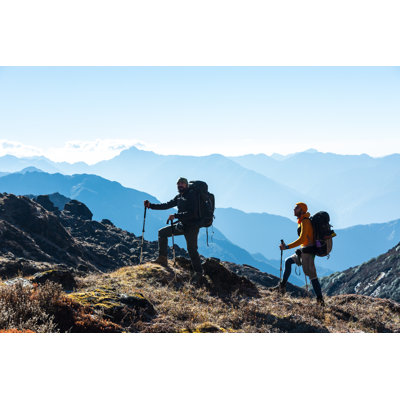 Silhouettes Of Two Hikers In Front Of Morning Mountains View by AlexBrylov - Wrapped Canvas Print