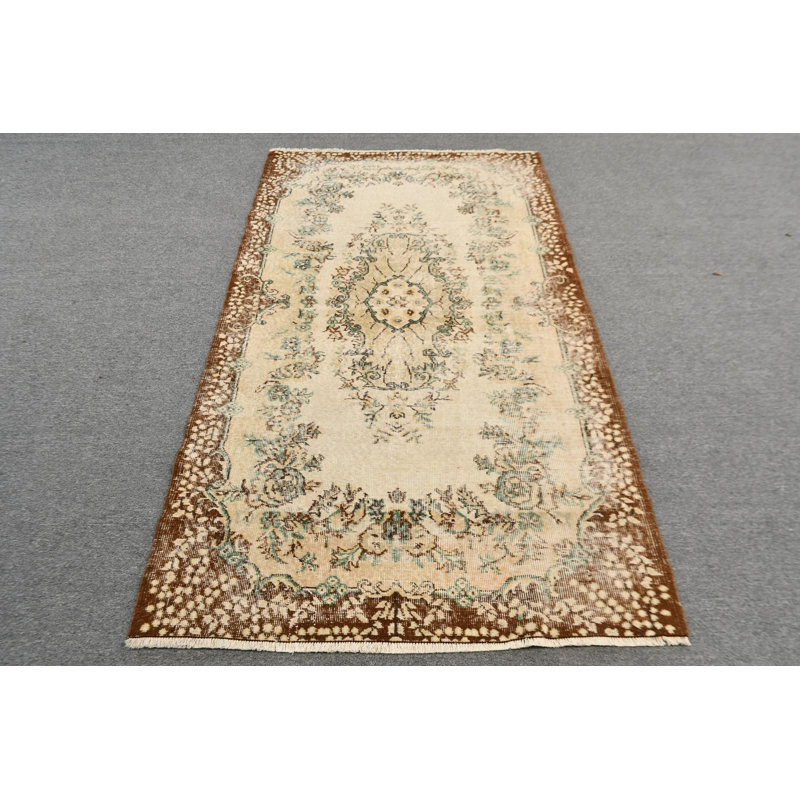 Tapis turc de style antique avec un élégant motif floral dans des tons bruns et beiges, idéal pour un décor traditionnel