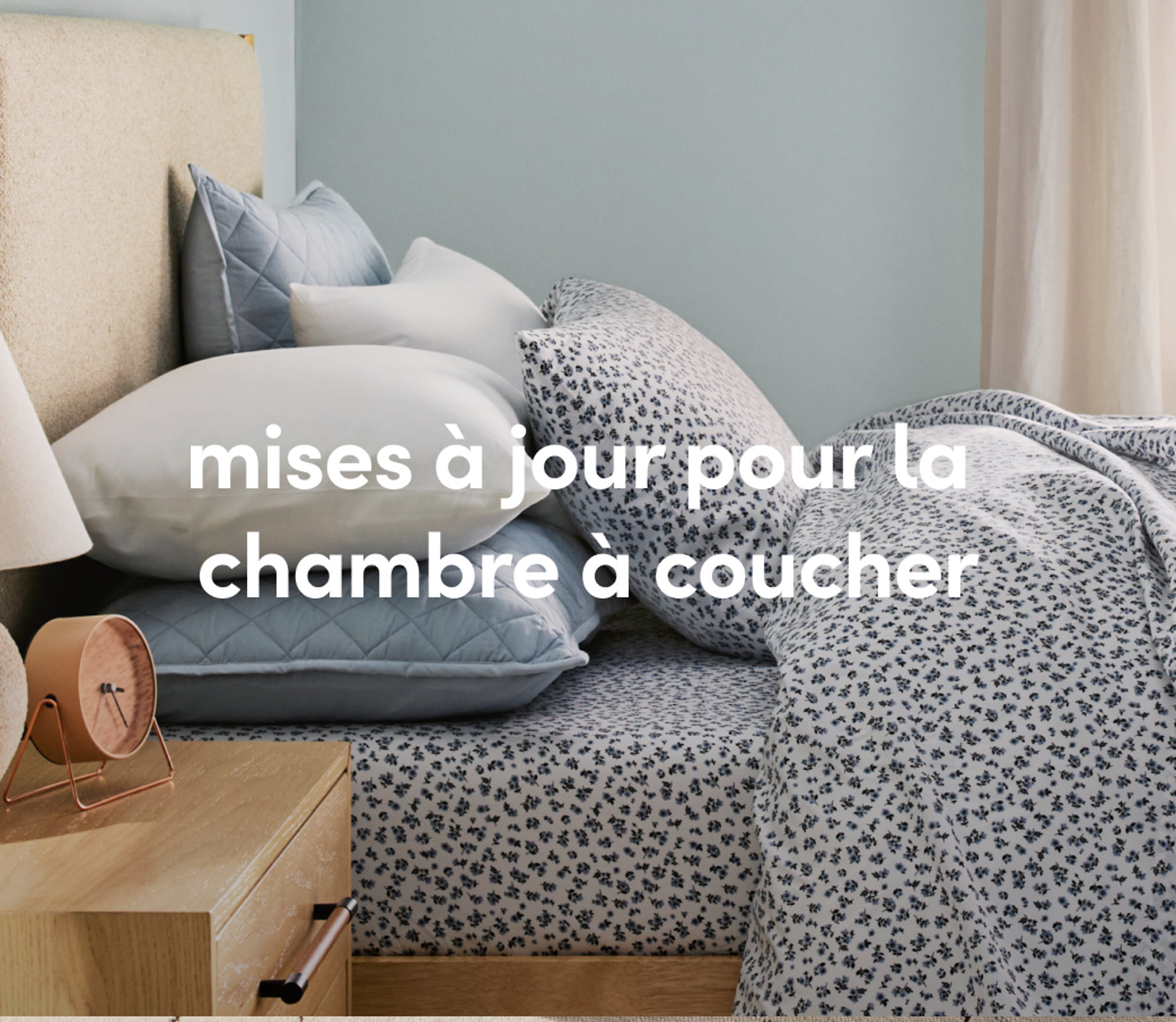 Une chambre confortable avec une literie à motifs tachetés, une table de chevet en bois et un éclairage chaleureux.