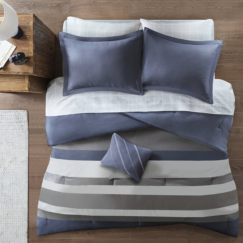 Lit avec édredon rayé bleu et gris et drap avec oreiller décoratif