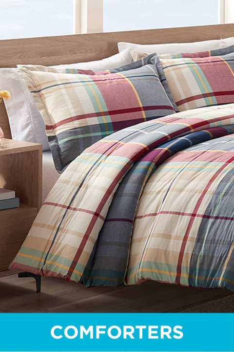 Plaid patterned comforter set on a bed with a wooden headboard, labeled Comforters.