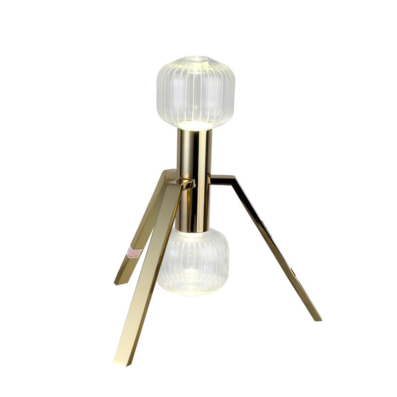 Cette lampe de table à DEL dorée unique avec abat-jour en verre