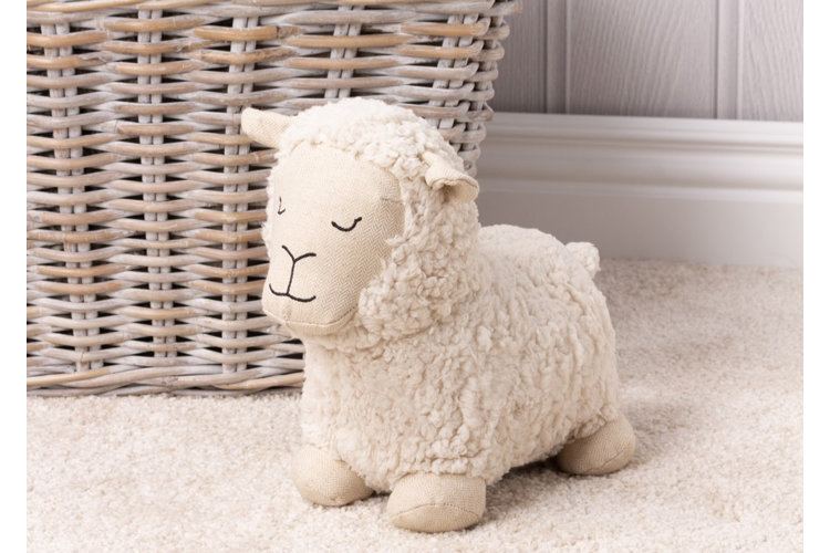 Plush wool sheep toy next to a wicker basket on a plush cream colored carpet
