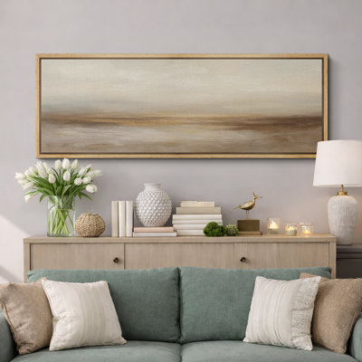 Panoramic abstract landscape canvas print in a light wood floater frame hanging above a living room console table.