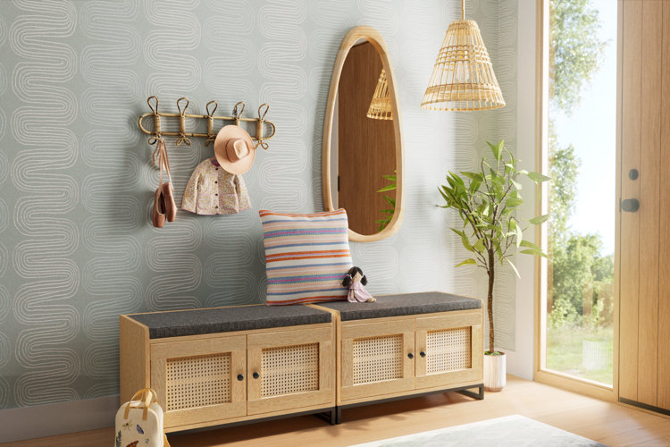 entryway with two rattan storage benches, abstract wallpaper, freeform-shaped wall mirror, and rattan accents