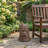 Odin tree stump statue table in brown resin with a carved face, displayed outdoors next to a garden chair.