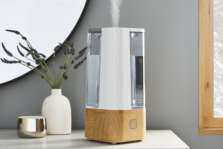 White tower-style humidifier in a corner with mist coming out.