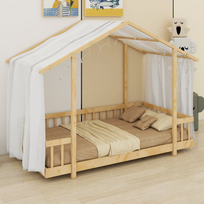 Un lit plateforme avec une structure en forme de maison, un ciel de lit transparent et des lumières scintillantes crée un refuge douillet pour les enfants.