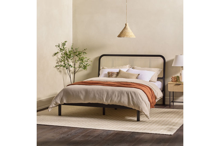 black metal and wicker headboard platform bed with beige comforter and white pillows