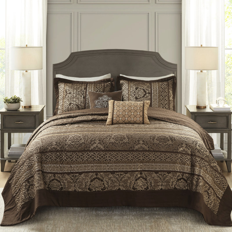 5 couvre-lits - grand. Brun et or. Comprend un couvre-lit, 2 taies décoratives et des coussins décoratifs. Fabriqué avec pour une durabilité de luxe. Affiche des feuilles, des rayures, des motifs. Surpiqûres ornées. Les détails dorés ajoutent de l'élégance.
