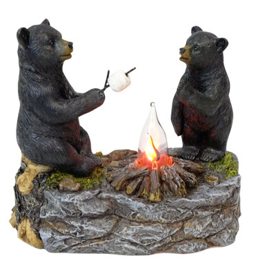 Ours noirs en polyrésine faisant griller des guimauves sur un feu de camp
