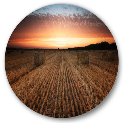 Paysage avec un champ plein de balles de foin au coucher du soleil
