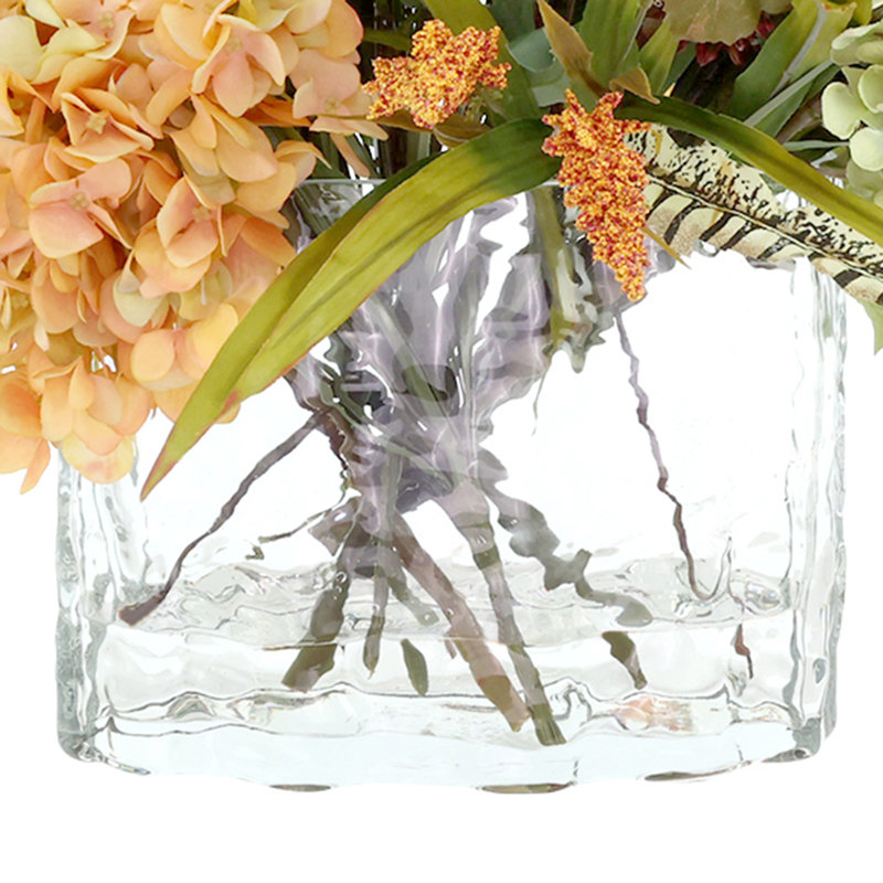 Heather, hortensia et chardon dans un vase en verre