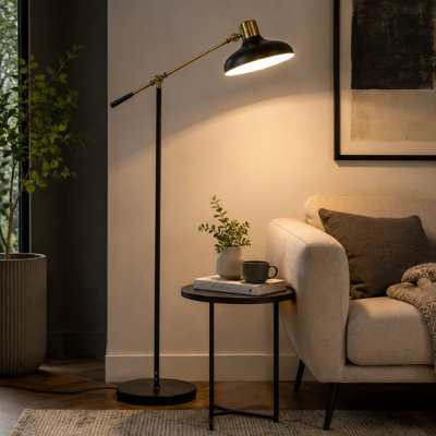 Lampe sur pied noire et dorée avec un bras long et équilibré; réglable en hauteur et convient aux salons et aux chambres à coucher.