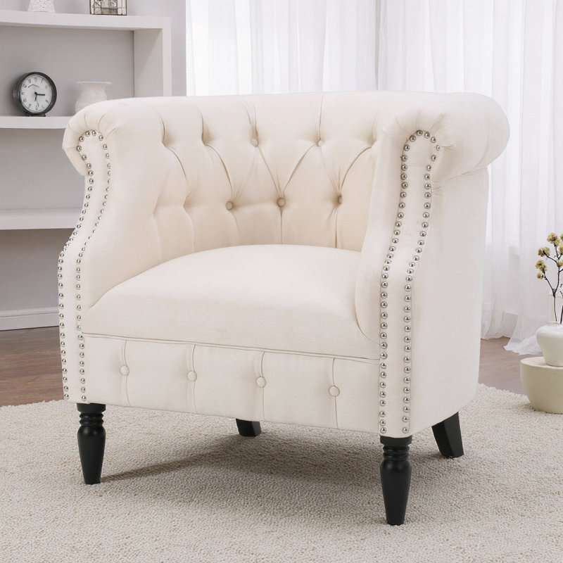 Élégant fauteuil club en tissu beige Akira avec dossier capitonné et accoudoirs cloutés, Tissu beige