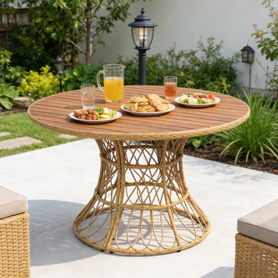 Table de jardin ronde en bois d'acacia avec piètement en osier, finition teck, 4 à 6 places, résistante aux intempéries.