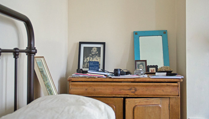 A messy dresser with paper and photo lenses cluttered on top.