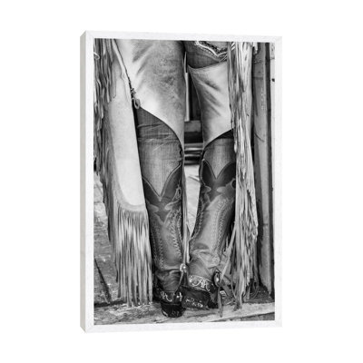 Horse Drive In Winter On Hideout Ranch, Shell, Wyoming. Cowgirl Detail Of Boots And Chaps In Doorway Of Log Cabin. by Darrell Gulin - Print on Canvas
