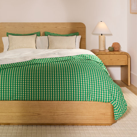 Bed with gingham duvet cover, mustard lumbar pillows.
