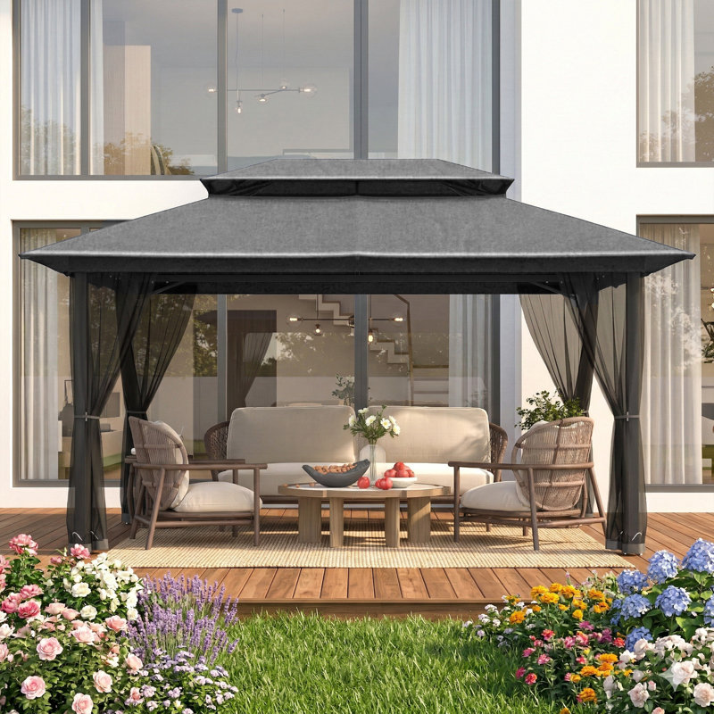 Dark gray gazebo with a double roof and black mosquito netting set up on a wooden deck with patio furniture.