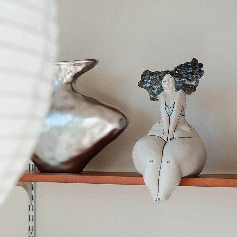 Objet décoratif en céramique représentant une femme assise aux courbes blanches