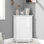 Armoire de salle de bain blanche triangulaire avec deux tablettes réglables pour les articles de toilette et les produits de nettoyage.