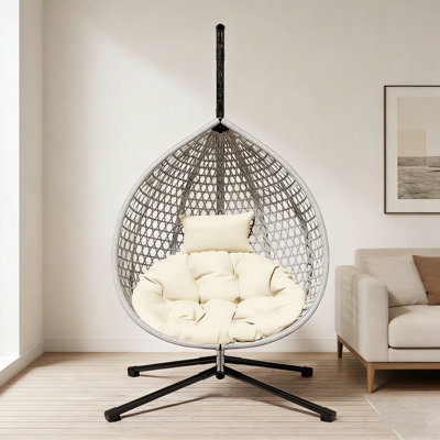 Chaise hamac robuste avec support, tissage en rotin durable et coussin amovible pour une utilisation intérieure et extérieure.