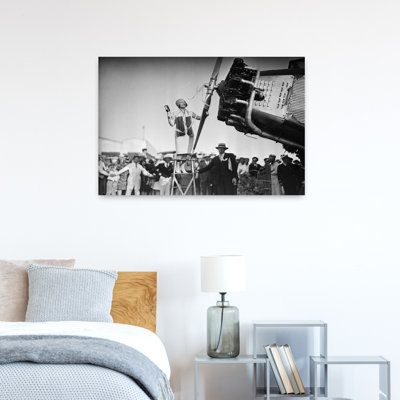 1920s ANNE LINDBERGH WIFE OF AVIATOR CHARLES LINDBERGH STANDING ON LADDER CHRISTENING AIRPLANE WITH BOTTLE OF CHAMPAGNE by American Stock - Wrapped Canvas Print