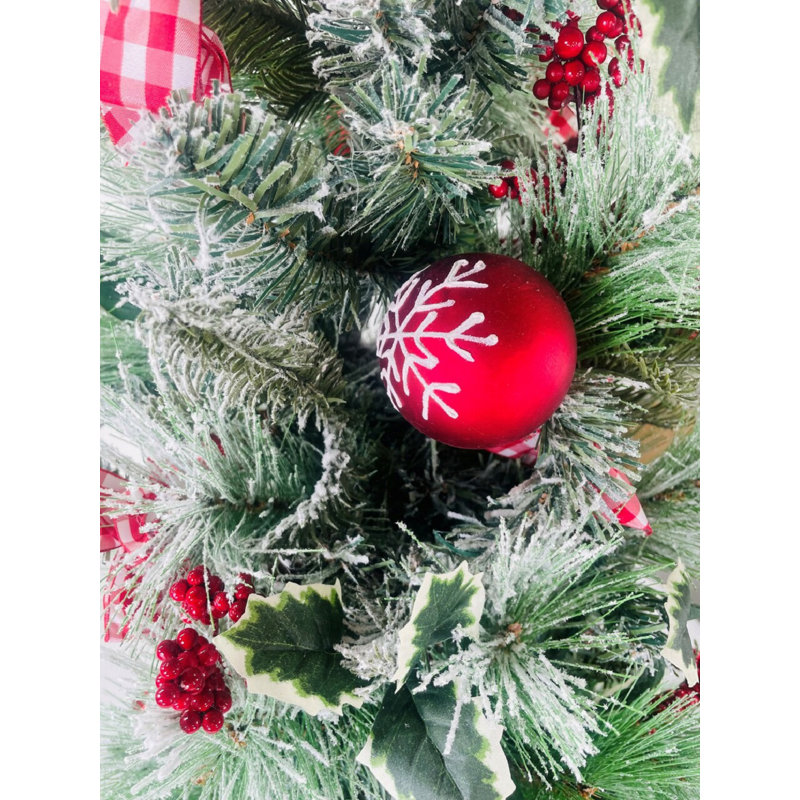 Arbre de Noël de table enneigé à feuilles persistantes avec ornements, baies et arcs non éclairés