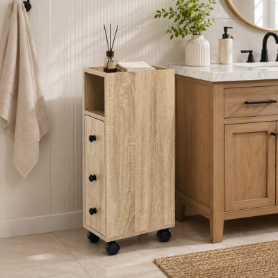 Armoire de rangement autoportante pour la salle de bain avec tiroirs doubles ouverts, un compartiment d'armoire à une porte et des tablettes de rangement au design intégré, quatre roulettes en bas et en chêne.