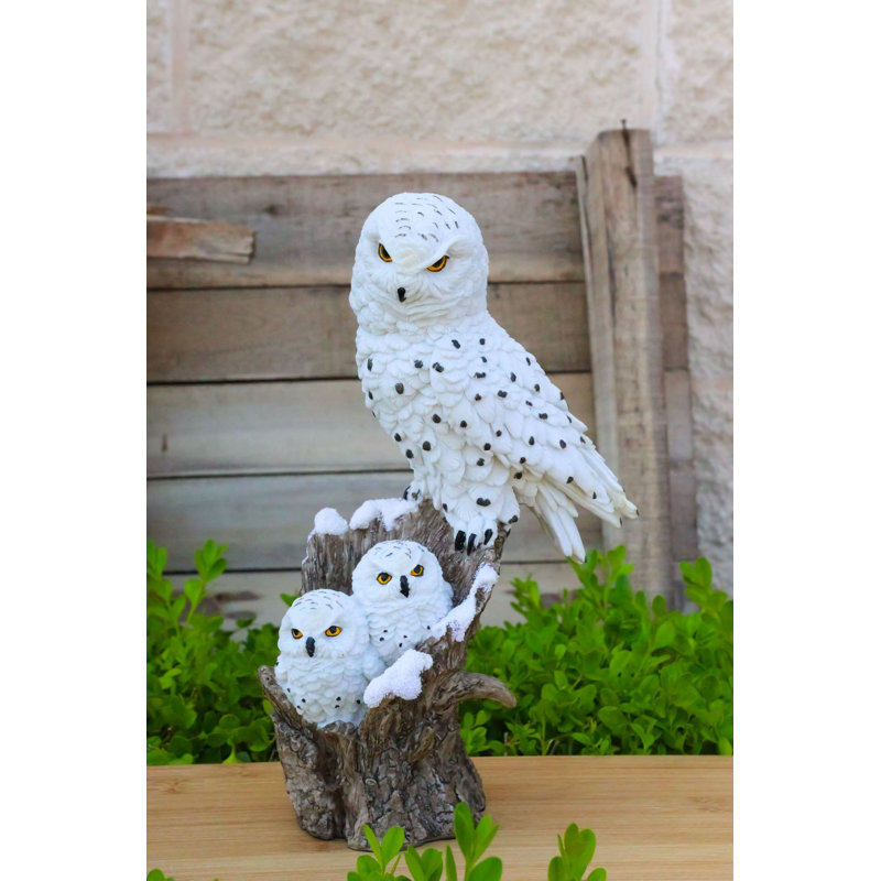 Figurine familiale représentant une chouette harfang des neiges et ses deux petits sur une souche d'arbre enneigée