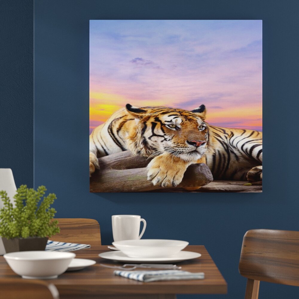 Leinwandbild Liegender Tiger mit Sonnenuntergang im Hintergrund