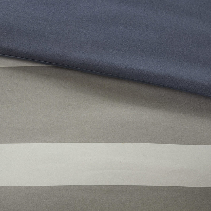 Lit avec édredon rayé bleu et gris et drap avec oreiller décoratif