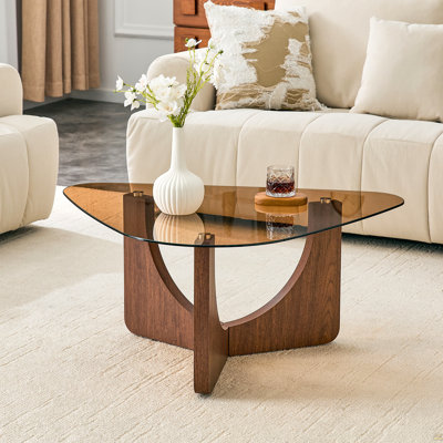 Table basse triangulaire de style rétro avec un plateau en verre trempé de couleur thé et des pieds triangulaires en MDF de couleur noyer. Idéal comme canapé, table d'appoint, table de coin, table basse portable pour le salon.