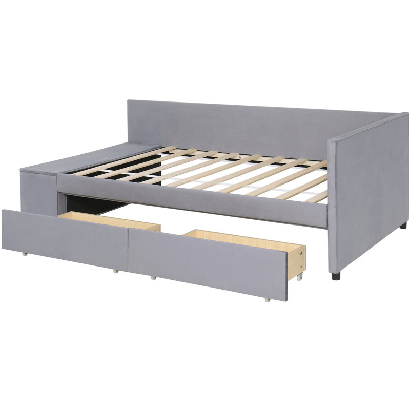 Lit simple tapissier en forme de L gris avec rangement. Revêtement en velours doux, tête de lit. Tiroirs pour la literie et les vêtements supplémentaires. Décoration latérale pour livres. Construisez une tête de lit confortable