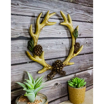 Couronne de bois de cerf avec pommes de pin, décor mural rustique pour chalet ou maison de campagne.