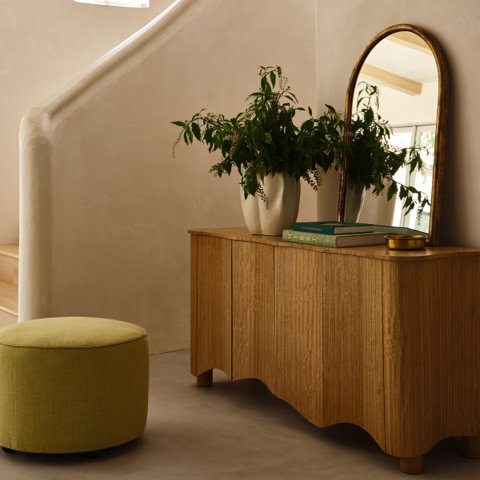 Entryway featuring a wood cabinet, mirror, ottoman, and stairs.