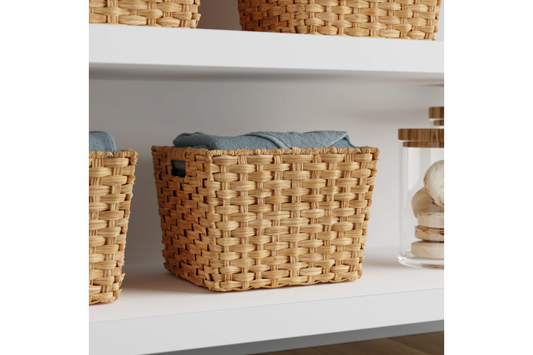 Close-up of a wicker storage basket on a shelf with a blue towel sticking out of the top.
