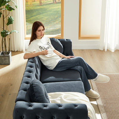 Canapé Chesterfield en velours avec deux coussins ronds, orné de clous cuivrés et de boutons capitonnés, et doté de pieds en métal. Un système de suspension permet d'accrocher des décorations décoratives.