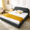 Grand lit à l'allure minimaliste moderne, tête de lit haute incurvée et stabilité durable dans un cadre rembourré gris foncé avec une tête de lit douce et confortable