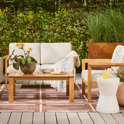 Outdoor seating area with sofa, chair, table, rug, and decor.