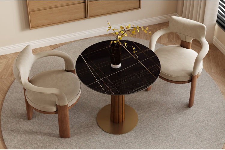 round pedestal dining table with black marbletop look paired with two upholstered dining chairs in neutral, modern dining space